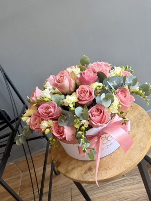 Aranjament Sunny Roses cu trandafiri roz și frezii albe, cu eucalipt, în cutie rotundă albă azalee.ro cu fundă roz