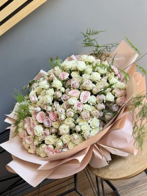 Buchet Rose Bonbon cu 85 miniroze în nuanțe pastelate de alb, roz și nude, cu plumosus, în ambalaj roz pudrat